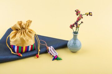 Korean traditional gift lucky bag with various decorations on yellow background.