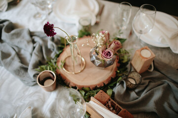 Vintage wedding decor. Beautiful event venue. Creative decoration. Hall decoration. Festive table decor. Stylish stone tablet with table number in grey, green branches and peonies, candles in gold can