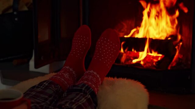 Feet in red woolen socks by a warm fireplace on a cold winters evening. Shallow depth of field.