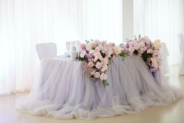 Vintage wedding decor. Beautiful event venue. Creative decoration. Hall decoration. Festive table decor. Stylish stone tablet with table number in grey, green branches and peonies, candles in gold can