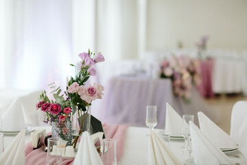 Vintage wedding decor. Beautiful event venue. Creative decoration. Hall decoration. Festive table decor. Stylish stone tablet with table number in grey, green branches and peonies, candles in gold can