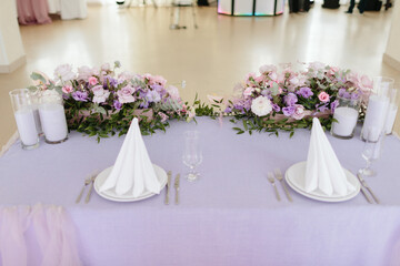 Vintage wedding decor. Beautiful event venue. Creative decoration. Hall decoration. Festive table decor. Stylish stone tablet with table number in grey, green branches and peonies, candles in gold can