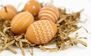 Close-up of natural brown eggs with white ornament marker on craft paper. Easter eggs with a pattern.