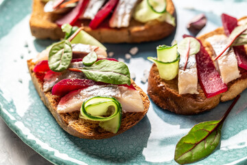 Herring fillet. Sandwich with salted herring, slice beetroot, green cucumber, onion and microgreen on the toasts. Scandinavian cuisine. Tradition Danish open sandwich. top view