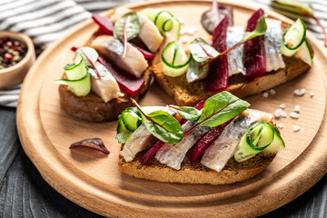 Herring fillet. Sandwich with salted herring, slice beetroot, green cucumber, onion and microgreen on the toasts. Scandinavian cuisine. Tradition Danish open sandwich. top view