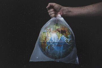 Close up male hold in plastic bag Earth world globe on black background. Save planet, planet is...