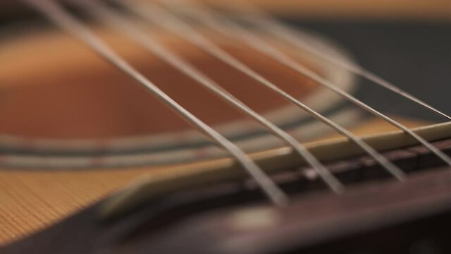 Close-up footage of guitar strings. man plays strings of yellow acoustic guitar. strings twitch to beat of music on stage or at home concert.