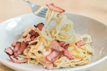 Spaghetti Carbonara with ham and bacon served on a dish.