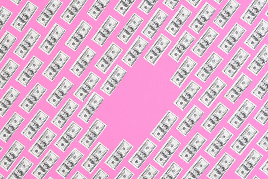 IRVINE, CALIFORNIA - 26 JAN 2021: Fake, mini USA 100 dollar bills arranged in rows on a pink background with blank space in the middle. Bills are not real currency, stage money.