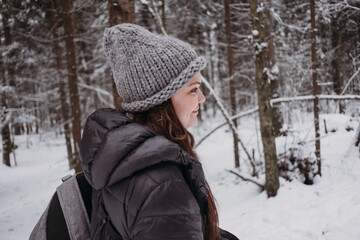 Fototapeta na wymiar Cheerful young caucasian woman in a winter snowy forest