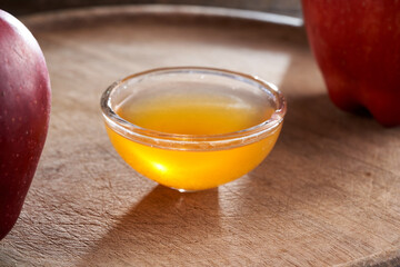 Apple cider vinegar in a bowl, with apples in the background