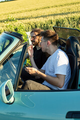 European young white models smiling outside one boy is lying on the car