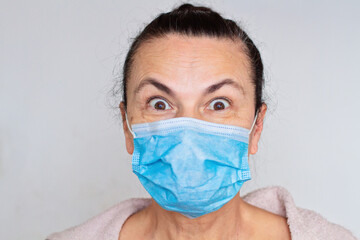 Woman aged in medical mask against coronavirus isolated on white shocked bulging eyes