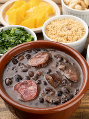 Traditional brazilian feijoada with orange, kale and manioc flour