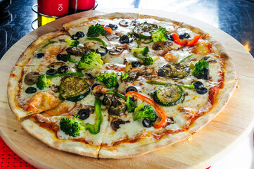 Italian pizza with various type of meat,broccoly and black olives