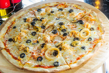 Italian pizza with various type of meat and black olives