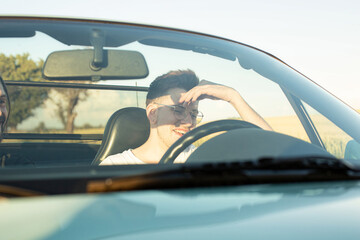 Naklejka premium Laughing young boy with blonde hair with hand near the face in the car