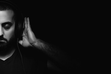 Billboard format. International DJ Day. Portrait of bearded musician in headphones on black isolated background