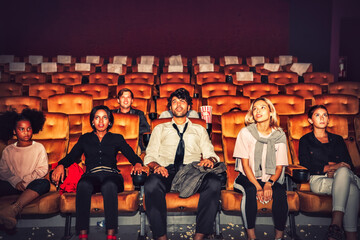 Group of people, adults and children sitting in the front row, enjoying for leisure entertainment in the modern cinema