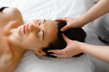 Obraz na płótnie Canvas Close-up of a beautiful woman receiving a head massage in a Spa center