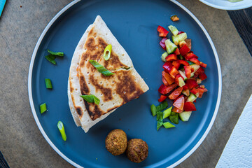 Fresh gluten free tortilla wrap stuffed with falafel, fresh vegetables salad, fried onion rings, jalapenos, mayo and scallions. Healthy and tasty meal preparation. Top view.