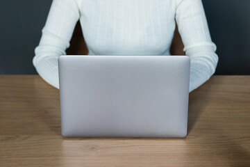 Fototapeta premium woman in white sweater working with laptop in office