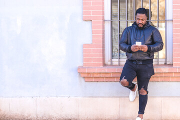 Dark-skinned man looking at the phone in the street.