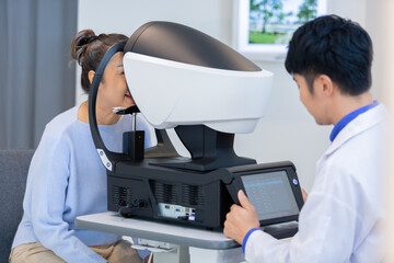 middle aged asian woman examining eyesight modern machine equipment by an eye specialist in clinic.