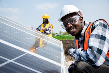 Two workers technicians installing heavy solar photo voltaic panels to high steel platform in corn...