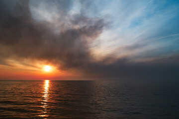 Naklejka na ściany i meble Sea sunset. Smoke wildfires sweeping across the sky.