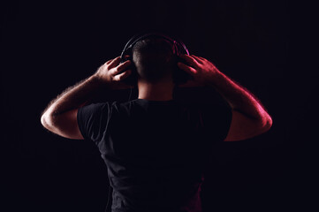 Back of dj in headphones clapping hands on black isolated background. International DJ Day