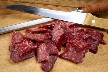 Sliced flat sausage on wooden table