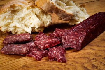 Sliced flat sausage and bread on wooden table