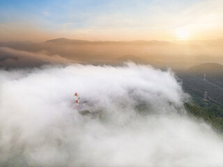 Aerial view, Beautiful Panorama landscape sunrise over peak Mountain with mist and warm light sunrise at signal repeater station pole,  Communication technology concept. Mae Moh Lampang, Thailand