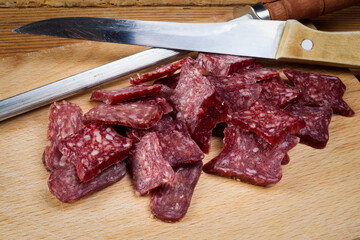 Sliced flat sausage on wooden table