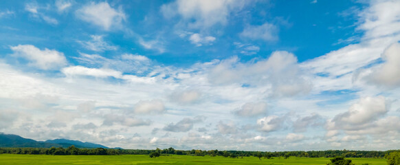 Panorama of sky and hills covered with trees. Good for banners. Green farm and blue sky with cloud, Rainy season landscape with clouds in the sky,  meadow field against the sky with clouds