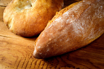 Round loaf and bread on wooden table