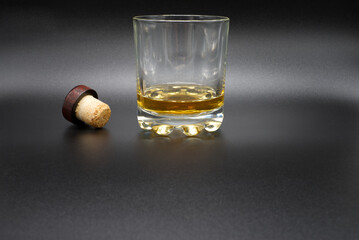 a glass of whiskey with a cork stopper