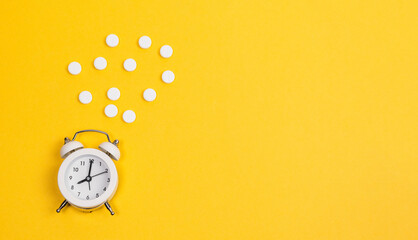 Alarm clock and contraceptive pills, studio shot on a yellow background, Safe sex and reproductive health concept. copy space