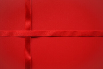 Red satin ribbon across red background, Love or Gift background concept 