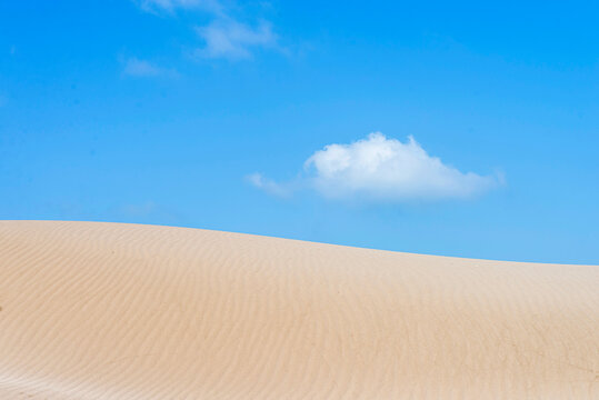 Sand dune under a blue and cloudy sky