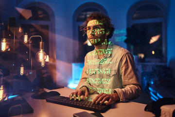Fototapeta na wymiar Portrait of a caucasian freelancer with glasses looking forward and thinking in dark office room with lights.