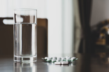 Medicine with drinking water on table at home