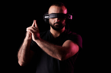 Young bearded hipster musician DJ listens to music on headphones and made his fingers in the form of pistol on black background. International DJ Day