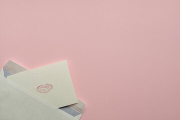 Handmade postcard with mark of lips from envelope on pink background
