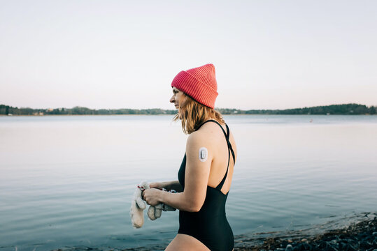Woman entering the calm water ready for cold water swimming in Sweden