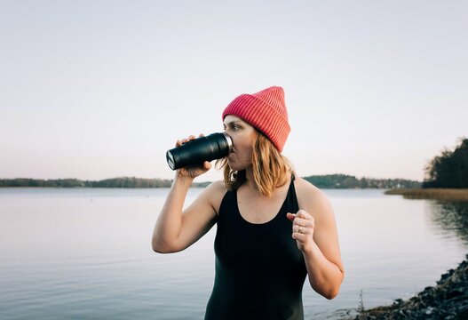 nordic woman drinking hot drink after cold water swimming in the sea