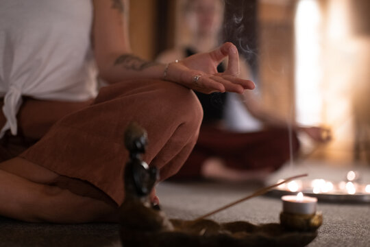 Anonymous female meditating near incense smoke