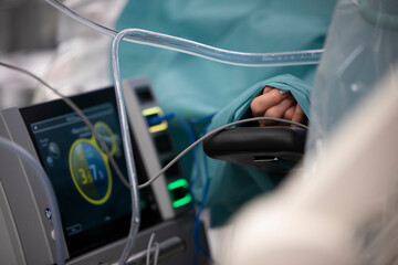 A patient's hand appears through a sheet in the operating room