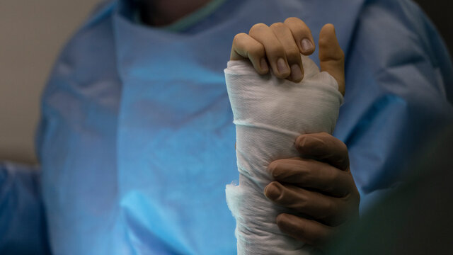 A surgeon holds the wrist of an operated patient in the operating room